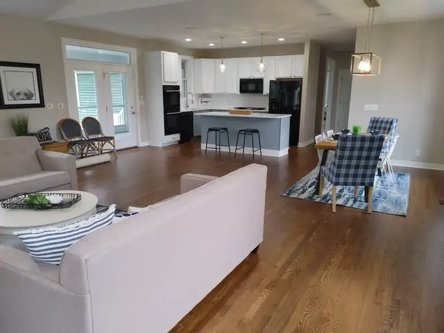 Open main floor with a white kitchen, gray island and dining area flowing into the living room