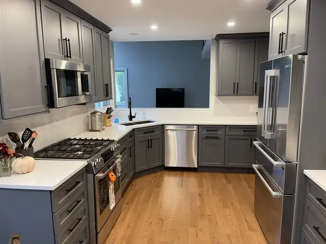Kitchen remodel with gray Shaker cabinets, white quartz counters, stainless appliances and oak floors